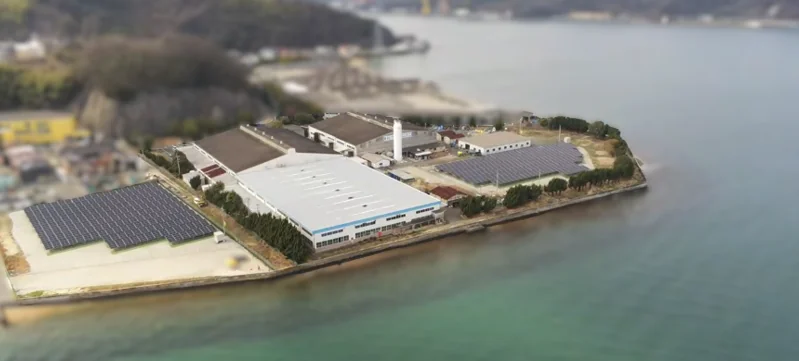 海沿いの工場と、敷地内の太陽光パネルの空撮写真